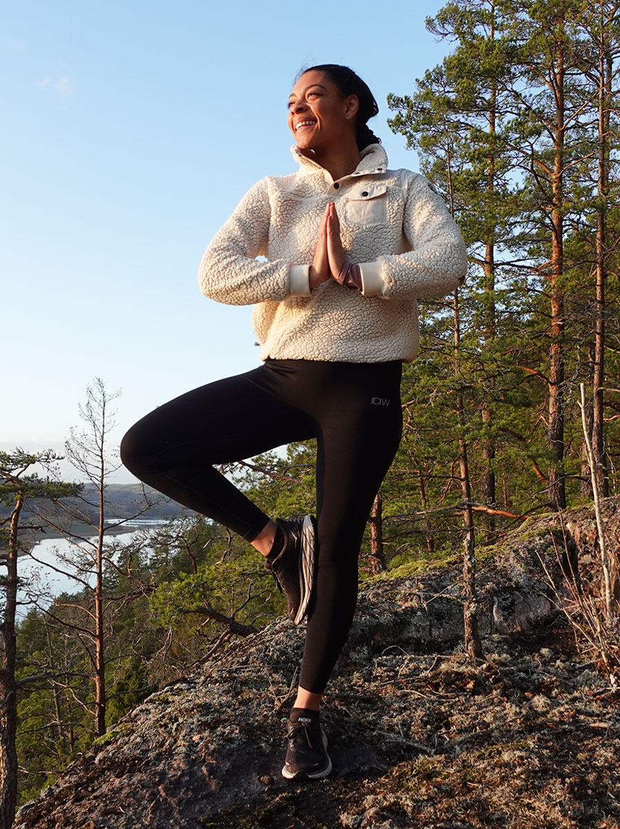 Coach gör en yogaställning ute i en skog