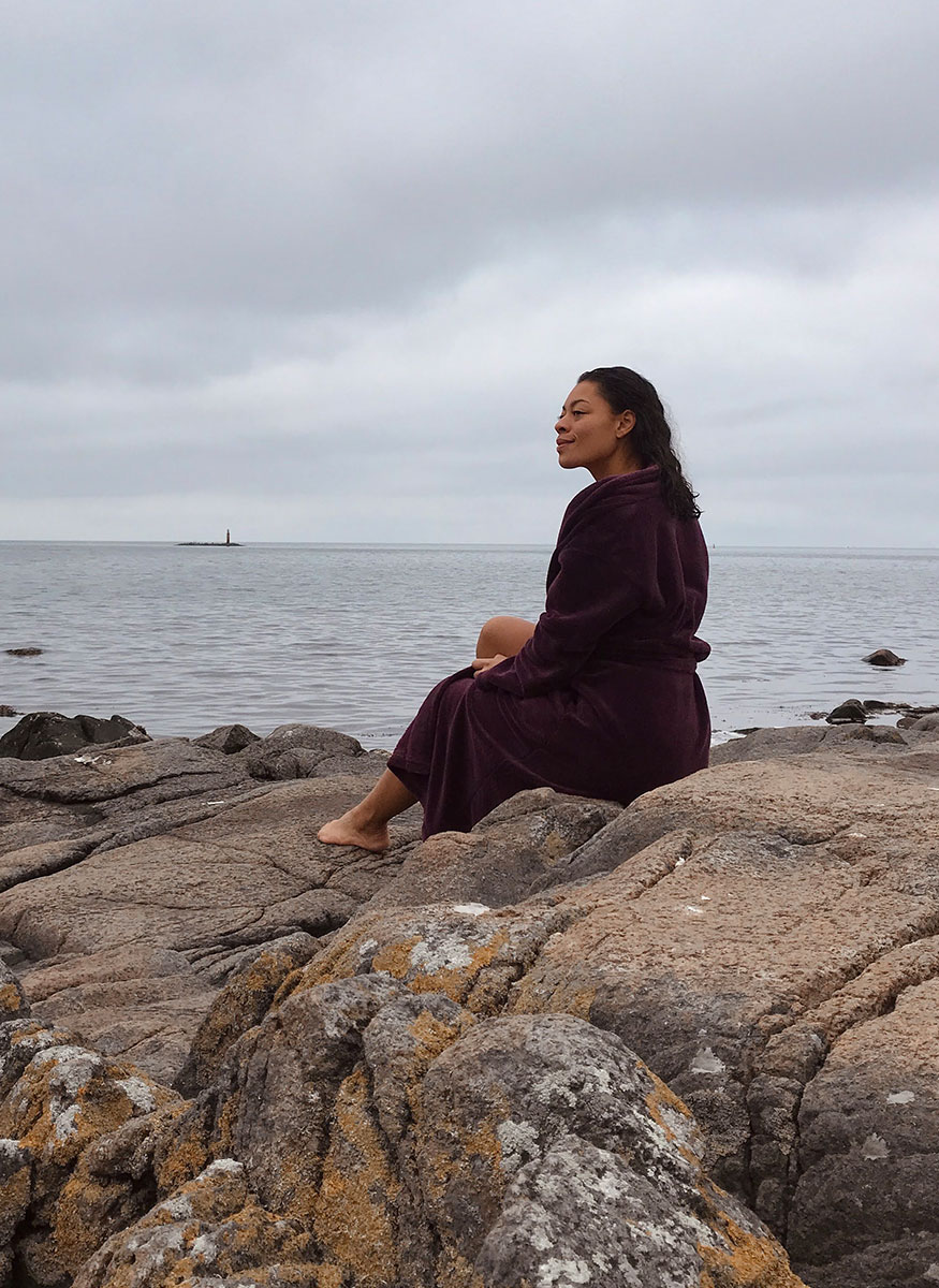 Coach sitter på klippor mot havet